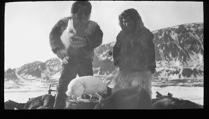 Image of White man holds hare; Inuit boy